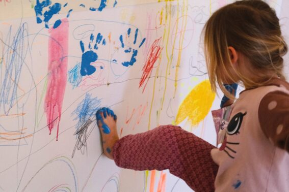 Barn maler med fot på vegg av papir :foto