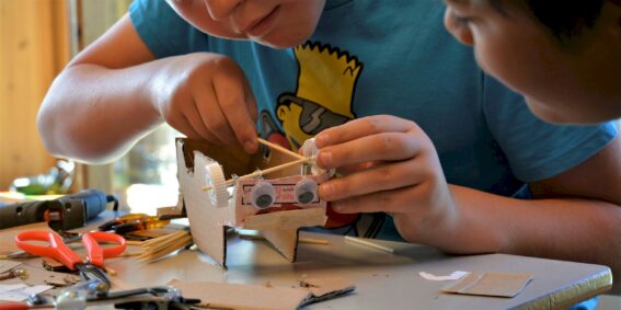 Barn som lager figur av papp :foto