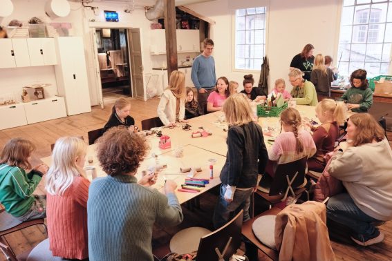 voksne og barn lager figurer sammen på verksted